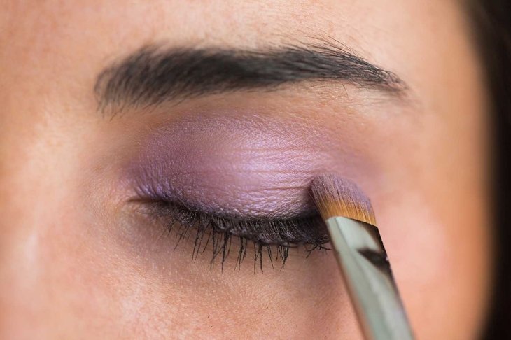 Woman getting purple eye shadow applied