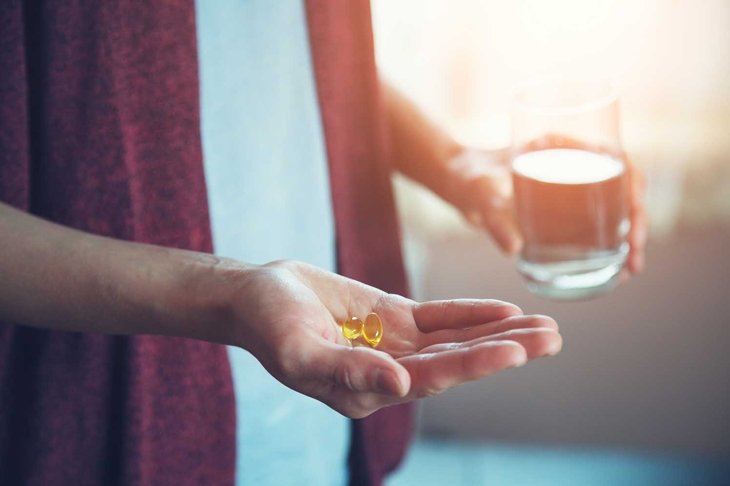 young woman taking pills, golden fish oil capsule, omega-3 supply, health care, morning sunshine background