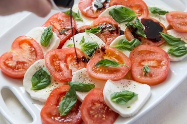 Pouring balsamic reduction on caprese salad