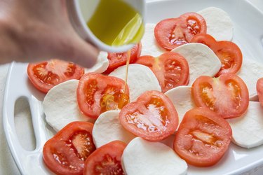 drizzling olive oil over caprese salad