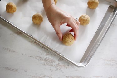 Placing rolled cake ball onto parchment-lined baking tray