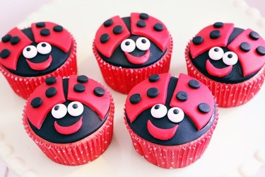Cupcakes decorated with cutouts of black and red fondant, to give them the appearance of cheerful ladybugs.