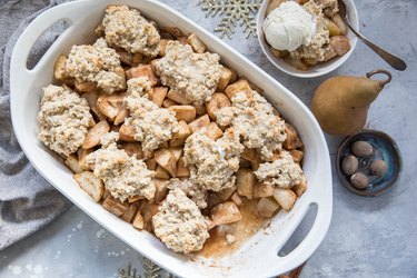 casserole dish of pear cobbler with a bowl of pear cobbler and a fresh pear