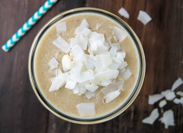 A bird\'s eye view of a coconut cream pie smoothie sprinkled with coconut flakes.