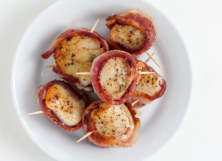 Two skewers filled with freshly grilled bacon-wrapped scallops.